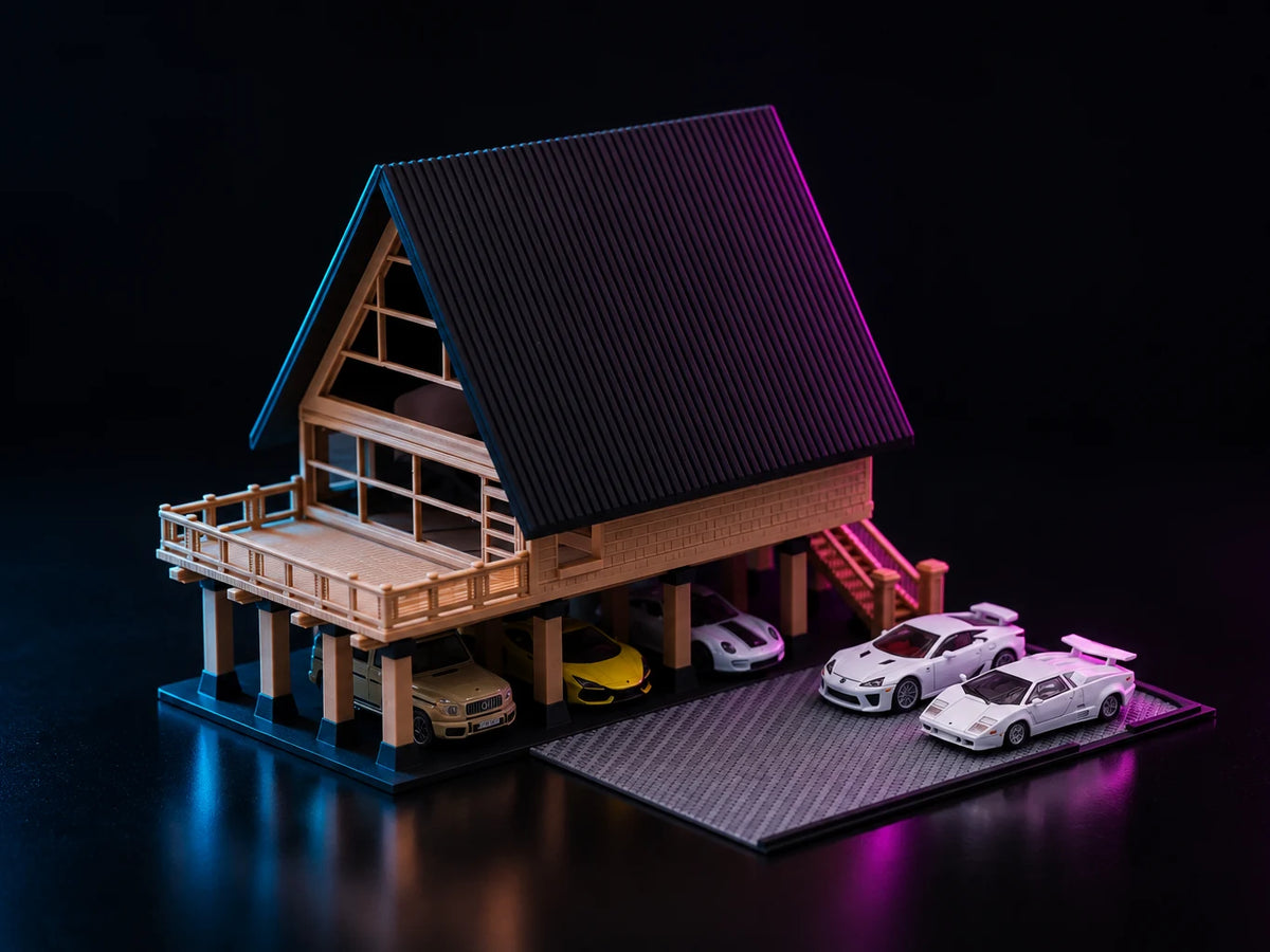 A printed A-frame house lit in cyan and magenta, raised on timber piers with a steep dark gable, a railed deck and cars parked underneath.