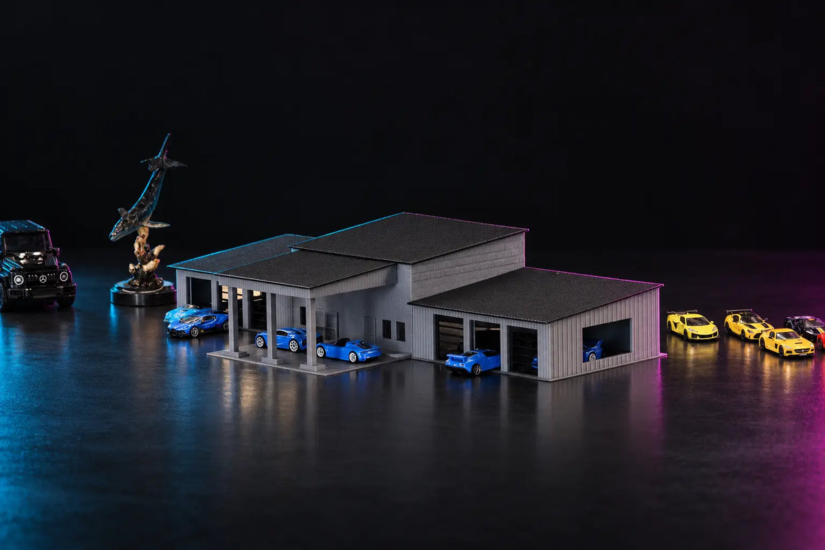 The printed collector garage in grey under dark roofs, blue cars under the columned carport and in the bays, lit cyan and magenta.