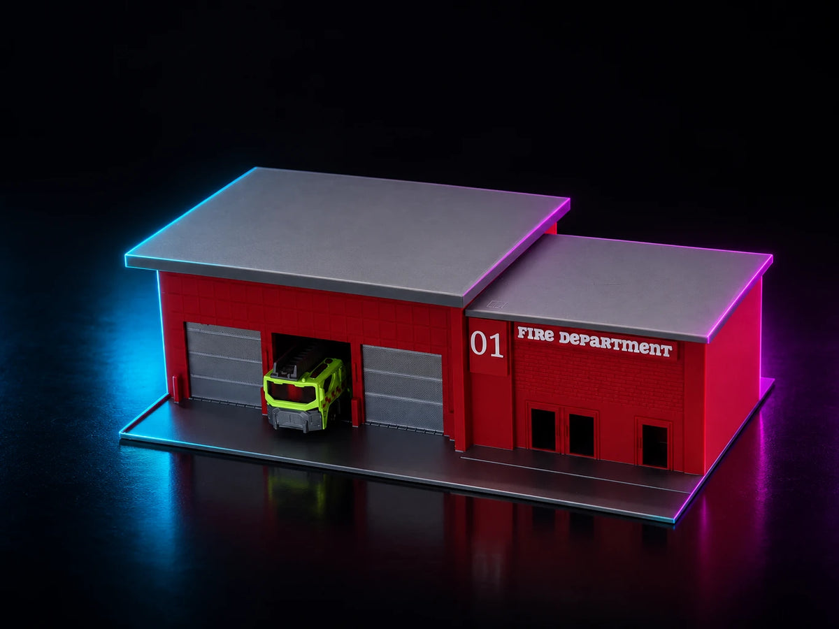 A printed fire station in engine red with a silver roof, two bays with one door open and a truck inside it.