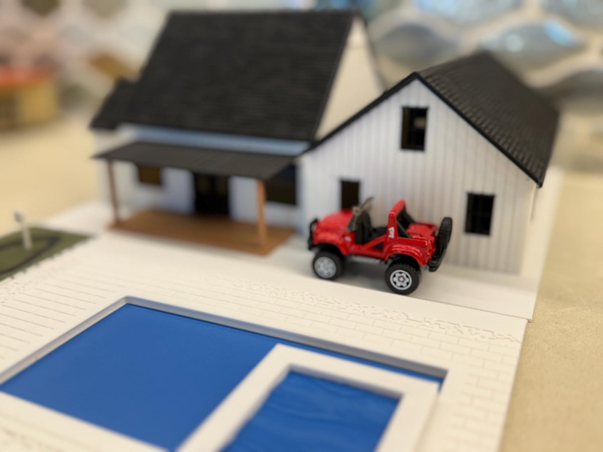 Red diecast off-roader parked by the pool behind the 1:64 modern farmhouse