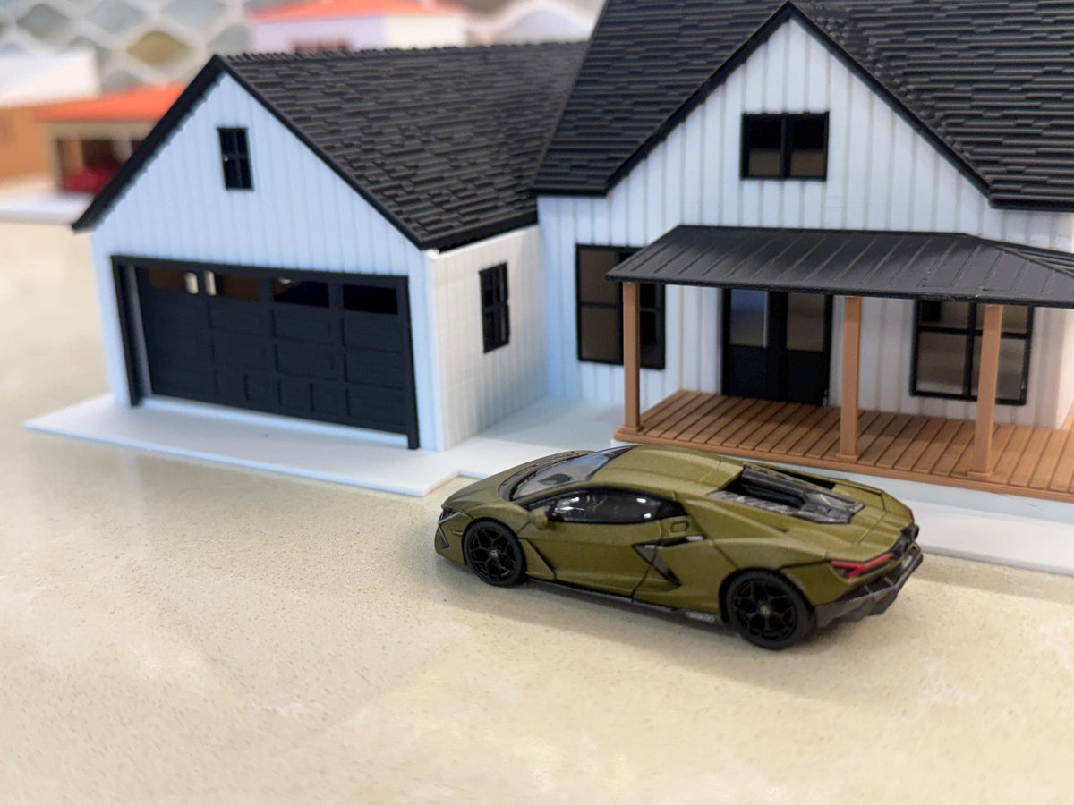 Olive diecast supercar in front of the two-car garage and porch of the 1:64 modern farmhouse