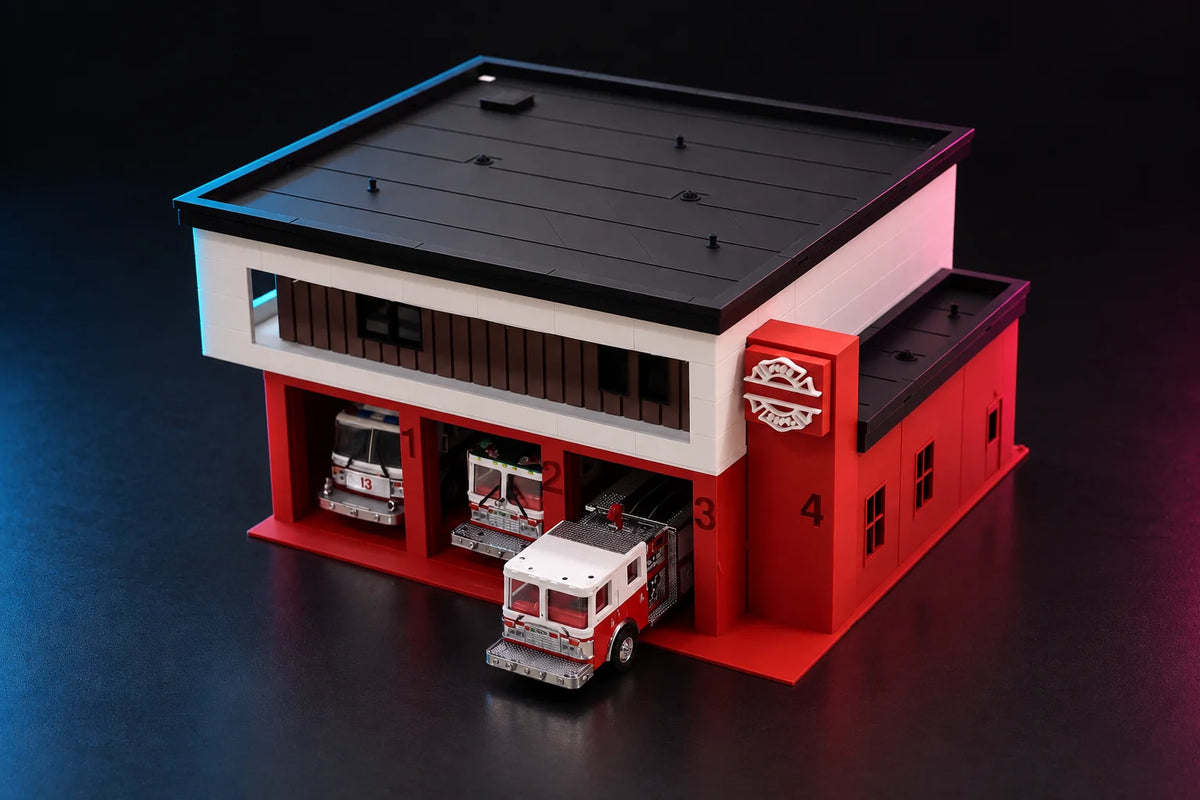 1:64 modern fire station with a diecast pumper rolling out of bay 3, FIRE DEPT. Maltese cross sign on the corner tower