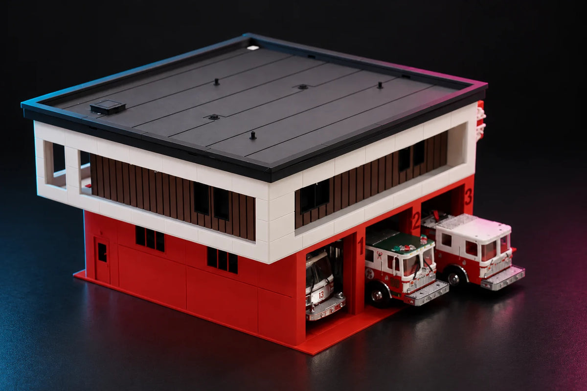 Side view of the 1:64 modern fire station, diecast engines nosed out of all three bays under the white upper floor