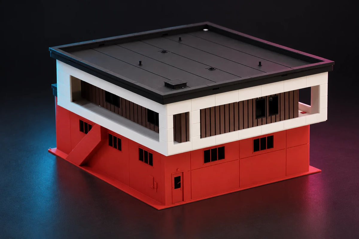 Rear of the 1:64 modern fire station diorama, an exterior staircase climbing to the white upper floor