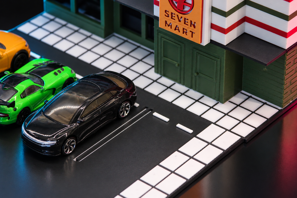 Parking lot detail of the 1:64 convenience store diorama, diecast cars beside the white tiled sidewalk