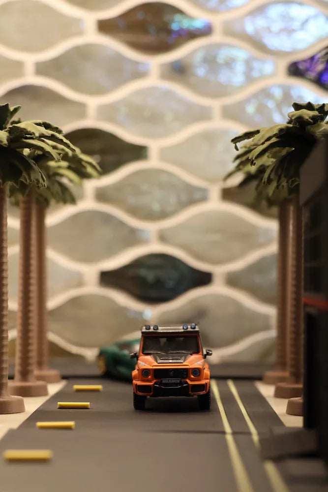 A road running straight away from the camera between rows of palms, an orange four-wheel drive coming down it.