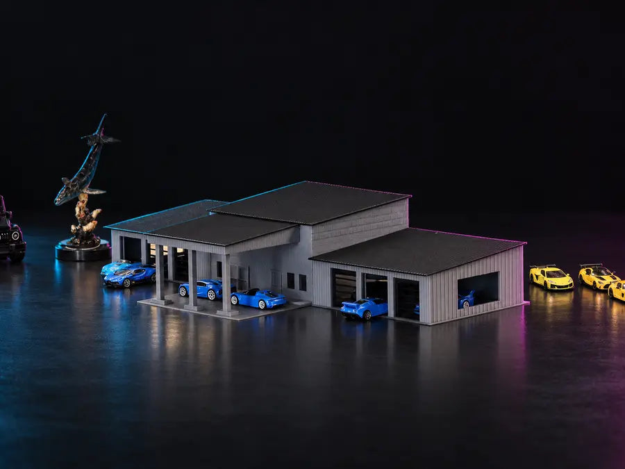 The printed collector garage in grey under dark roofs, blue cars under the columned carport and in the bays, lit cyan and magenta.